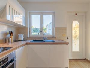 een keuken met witte kasten, een wastafel en een raam bij Holiday Home Victoria by Interhome in Zaton