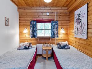 2 Betten in einem Zimmer mit Holzwänden und einem Fenster in der Unterkunft Holiday Home Sotka 13 by bomba by Interhome in Nurmes