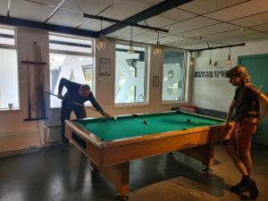 two men playing pool in a room with a pool table at SKAP Hostel Mandal in Mandal