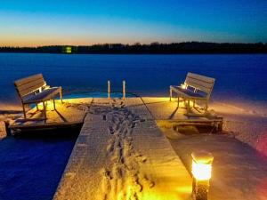 two benches sitting on a dock next to a body of water at Holiday Home Villa keidas by Interhome in Pertunmaa