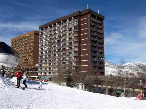 a group of people on skis in the snow in front of a building at Apartment Baikonour-8 by Interhome in Le Corbier