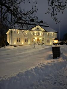 a white building with lights in the snow at night at Forsså Herrgård hotell och SPA in Näsviken