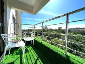 balcón con vistas y 2 sillas blancas en Midtown Executive Suites With Balcony, King Bed en Nakuru