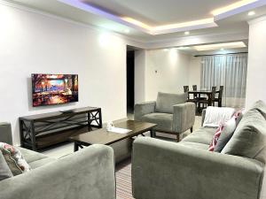 Midtown Executive Suites With Balcony, King Bed في ناكورو: غرفة معيشة بها كنب وكراسي وطاولة