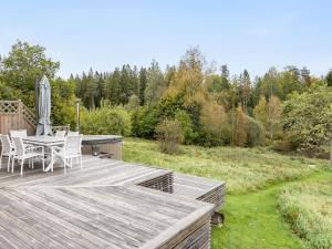 une terrasse en bois avec une table et des chaises. dans l'établissement Holiday Home Älmegården - SND127 by Interhome, à Lammhult