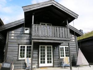 a wooden house with a balcony and two chairs at Holiday Home Hovden - SET086 by Interhome in Hovden