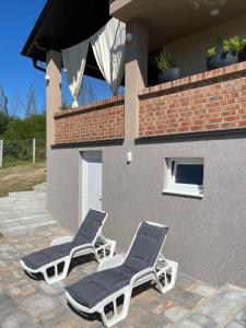 two lounge chairs on a patio in front of a house at Vikendica Villa Ramona Banja Luka in Banja Luka