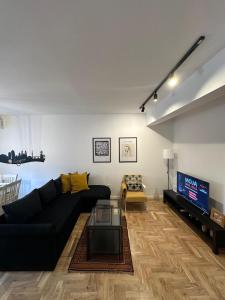 sala de estar con sofá negro y TV en Optimal Apartment Sarajevo en Sarajevo