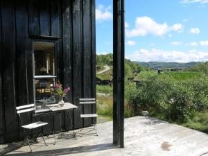 a black house with a table and chairs on a deck at Holiday Home Morgenro - SOW160 by Interhome in Åseral