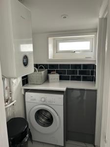 eine Waschküche mit einer Waschmaschine und einem Fenster in der Unterkunft Modern 1 bed Flat with Private Courtyard in Newport