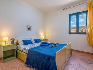 a bedroom with a bed with blue sheets and a window at Apartment L'Oasi Trilo A3 by Interhome in Trinità dʼAgultu