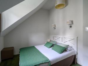 een witte slaapkamer met een bed met groene kussens bij Villa Le Château de Kergonano-5 by Interhome in Baden
