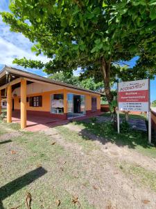 a building with a tree and a sign in front of it at Recanto Aconchego Itapoá in Itapoa