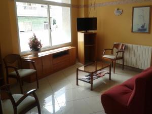sala de estar con TV, sillas y mesa en Hotel Paraíso Del Marisco, en O Grove
