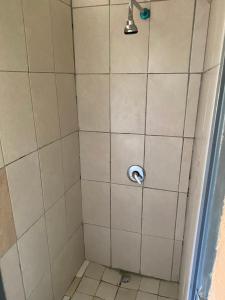 a shower with a white tiled wall and a shower head at Good Life Guest house in Orkney +27731671754 in Orkney