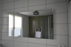 een spiegel aan een muur in een badkamer bij Zeewind en Zonneschijn in Oostburg