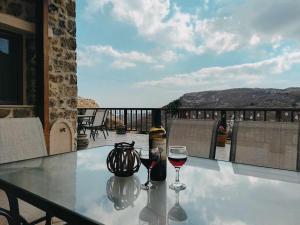 a table with two glasses of wine on a balcony at VILLA CASTELLOS in Priniás