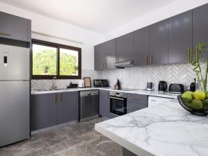 a kitchen with gray cabinets and a marble counter top at Cocoon Ocean Villa Luxury Escape in Peyia