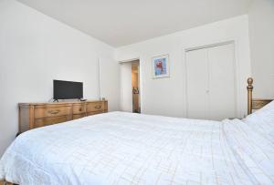 - une chambre blanche avec un lit et une télévision sur une commode dans l'établissement Coquette 3.5 pour 4 personnes, à Montréal