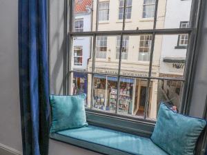 um assento de janela com almofadas azuis em frente a uma janela em Book House em Whitby
