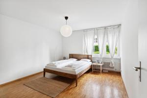 1 dormitorio blanco con 1 cama y 2 ventanas en Beautiful Boutique Apartment DRAHTZUG14, en Zúrich