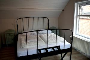 1 dormitorio con 1 cama con sábanas blancas y ventana en Zeewind en Zonneschijn, en Oostburg