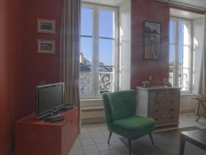 ein Wohnzimmer mit einem grünen Stuhl und einem TV in der Unterkunft Appartement Le Palais, 2 pièces, 4 personnes - FR-1-418-71 in Le Palais
