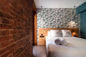 a bedroom with a white bed and a brick wall at Hotel Atari in Donostia-San Sebastián