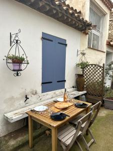 una mesa de madera con sillas y una puerta azul en Les lauriers rouge, en Peyriac-de-Mer