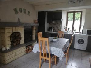 a kitchen with a table and a fireplace in a kitchen at LE GITE DE LA MAISON ROUGE in Anctoville