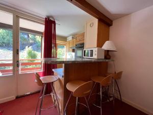 a kitchen with stools and a counter with a microwave at Appartement Enchastrayes, 2 pièces, 6 personnes - FR-1-165A-26 in Enchastrayes