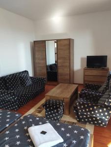 a living room with couches and a table and a tv at Panoráma apartman in Pécs