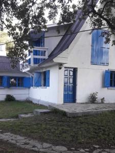 Casa blanca con ventanas azules y puerta azul en Cabaña frente al Río en Necochea