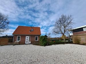 a small house with a red roof on a gravel driveway at Vakantiewoning Seehouse in Oostkapelle