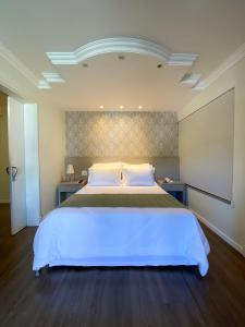 1 dormitorio con 1 cama blanca grande en una habitación en Caitá Hotéis, en Concórdia