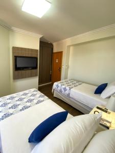 Habitación de hotel con 2 camas y TV de pantalla plana. en Caitá Hotéis, en Concórdia