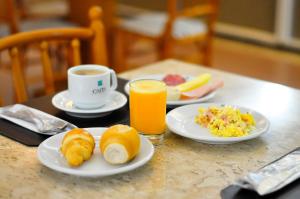 una mesa con platos de comida y una taza de zumo de naranja en Caitá Hotéis, en Concórdia