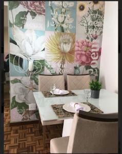 a dining table with two chairs and a floral wall at APTO 2Qtos na Asa Norte in Brasília