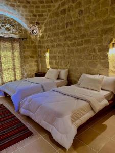 2 Betten in einem Schlafzimmer mit Ziegelwand in der Unterkunft Tache By The Lake in Al-Fayyūm