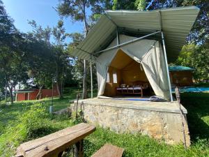 a tent in a field with a wooden bench at Sobaway Resorts in Ella