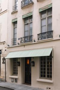 a building with a green awning and windows at H&ocirc;tel L de Lut&egrave;ce in Paris