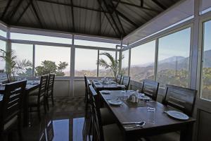 a dining room with tables and chairs and windows at Hotel Harmony Blue Mcleodganj, Dharamshala in Dharamshala