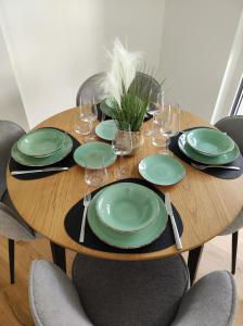 a wooden table with green plates and wine glasses at Roksox-home Apartment gegenüber der Uno-City und Kaiserwasser in Vienna