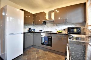 a kitchen with stainless steel appliances and brown cabinets at Manchester Townhouse by BEVOLVE - 4 bedrooms - Free Parking in Manchester
