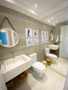een badkamer met een wastafel, een toilet en een spiegel bij APARTAMENTO 05 - PÉ NA AREIA - BARRA BALI - AL in Barra de São Miguel