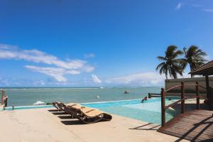 a swimming pool with a view of the ocean at APARTAMENTO 05 - PÉ NA AREIA - BARRA BALI - AL in Barra de São Miguel