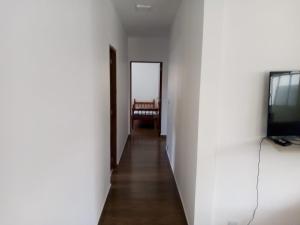 un corridoio con televisore e una stanza con tavolo di Casa com piscina em condomínio fechado a Peruíbe