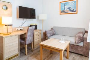 - un salon avec un canapé et un bureau avec une chaise dans l'établissement Hanse Appartement II Warnemünde, à Warnemünde