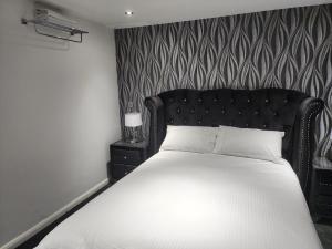 a bedroom with a white bed with a black headboard at Belfast Luxury Apartment in Belfast