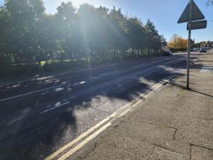 an empty street with the sun shining on the road at Belfast Luxury Apartment in Belfast